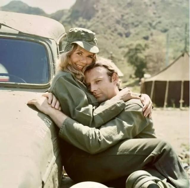 Loretta Swit (Margaret "Hot Lips" Houlihan) and Larry Linville (Major Frank Burns) share an intimate moment during a break on set, symbolizing their complicated relationship on M*A*S*H